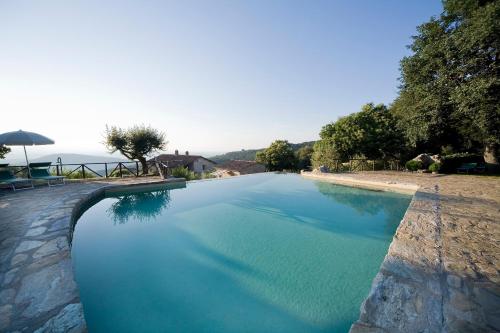 a large pool of blue water in a yard at Ripostena in Casole dʼElsa
