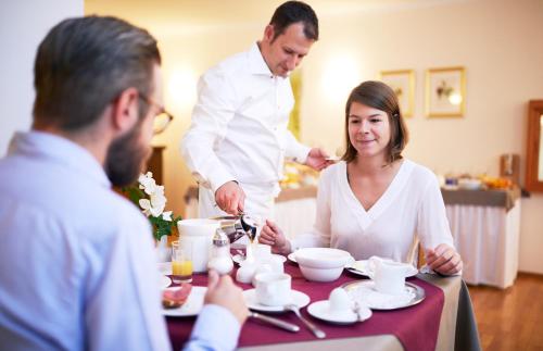 a man preparing food at a table with a woman at Hotel Alter Wirt in Hallbergmoos