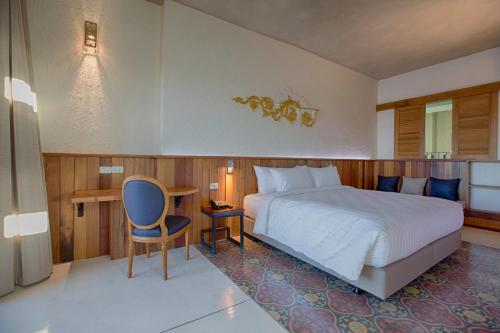 a bedroom with a bed and a desk and a chair at Natee The Riverfront Hotel Kanchanaburi in Kanchanaburi