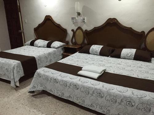 two beds in a hotel room with white and brown at Hostal Kin-Beh in Valladolid