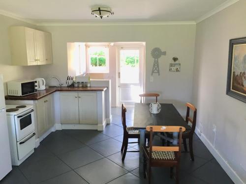 een keuken met een tafel en stoelen en een keuken met een fornuis bij Olive Cottage in Franschhoek