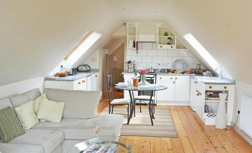 a living room with a couch and a table in a kitchen at Weavers Loft in Erpingham