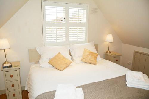 a white bed with two pillows and a window at Weavers Loft in Erpingham