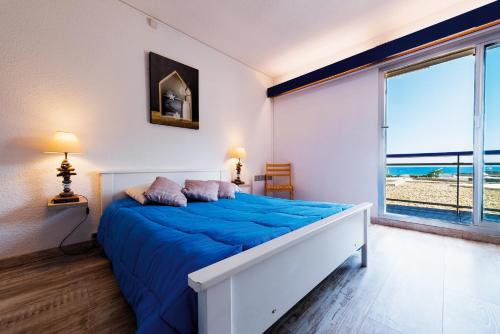 1 dormitorio con cama con sábanas azules y ventana en Lagrange Vacances Le Lydia Playa, en Le Barcarès