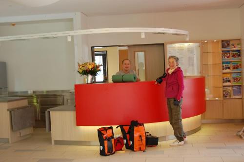 a woman standing next to a red counter with a man at Jugendherberge Ratzeburg am See in Ratzeburg