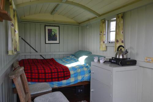 1 dormitorio con 1 cama en una habitación pequeña en Shepherd's Hut en Blandford Forum