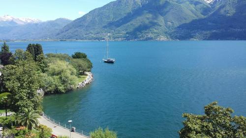 a boat in a large body of water with mountains at H4 Hotel Arcadia Locarno in Locarno