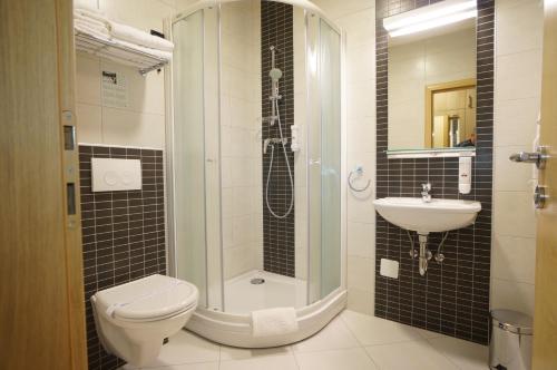 a bathroom with a shower and a toilet and a sink at Hotel Calypso in Zagreb