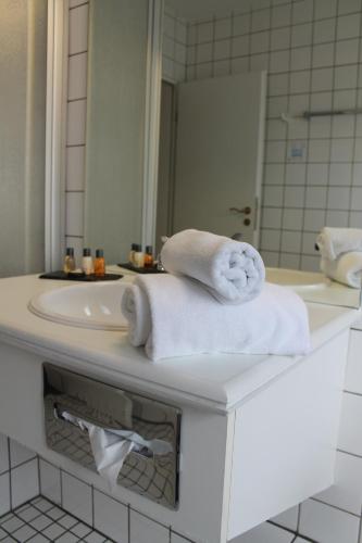 a bathroom with a sink and towels on a counter at Hotel Windthorst in Münster