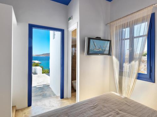 a bedroom with a door to a view of the ocean at Psathi Blue Alpha in Kimolos