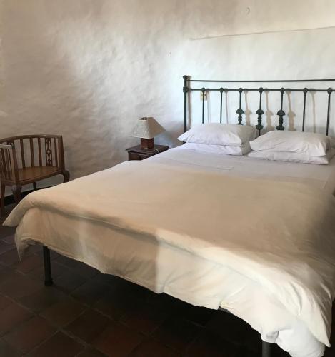 a bedroom with a large white bed and a chair at Club Hotel Casapueblo in Punta del Este