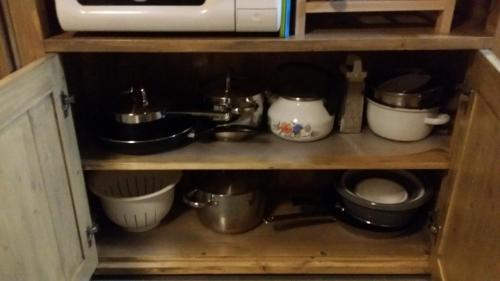 a kitchen shelf with pots and pans and a microwave at Chata Adavy in Liptovský Ján