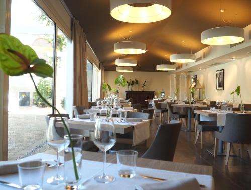 a restaurant with white tables and chairs and windows at Hotel De La Ville in Riccione