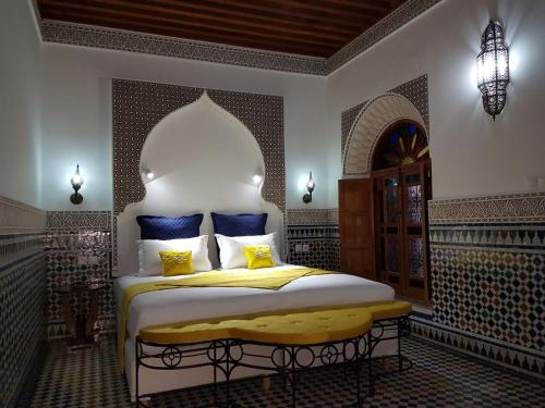 a bedroom with a bed with blue and yellow pillows at Riad Soleil d'Or in Fez