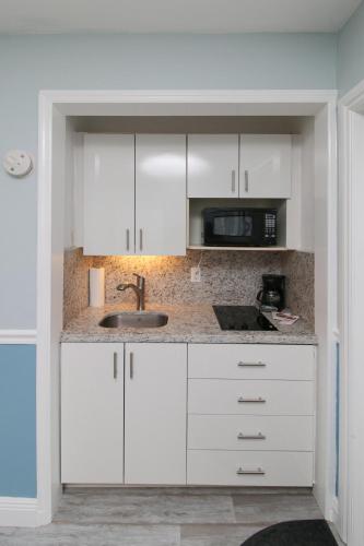 a kitchen with white cabinets and a sink and a microwave at The Dolphin Hollywood in Hollywood