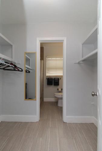 a white bathroom with a toilet and a mirror at The Dolphin Hollywood in Hollywood
