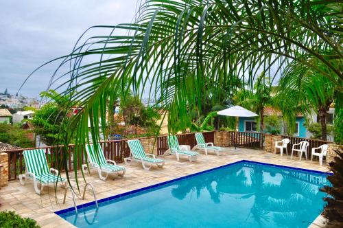 a swimming pool with chairs and a palm tree at Pousada Albacora in Bombinhas
