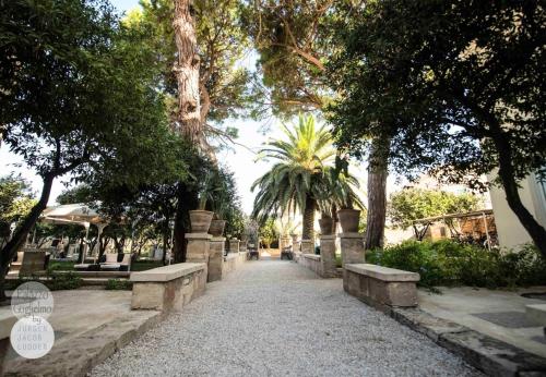 a walkway with benches in a park with trees at Palazzo Guglielmo in Vignacastrisi