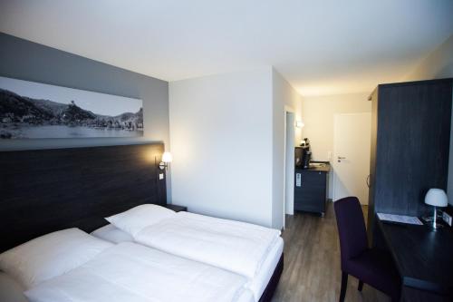 a bedroom with a white bed and a desk and chair at aparthotel Cochem in Cochem