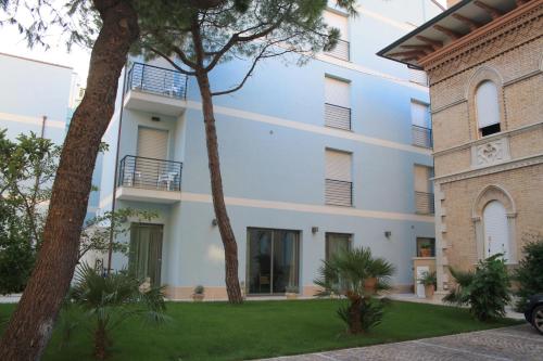 un edificio bianco con alberi di fronte di Hotel Chiaraluna a Civitanova Marche