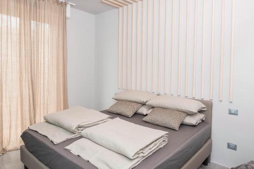 a bed with white pillows on it in a room at Green Flat in Bardolino