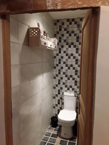 a bathroom with a toilet and a tile wall at Au Moulin de Valérie in Frencq