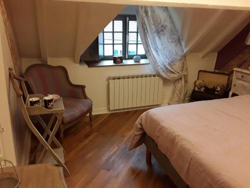 a bedroom with a bed and a chair and a window at Au Moulin de Valérie in Frencq