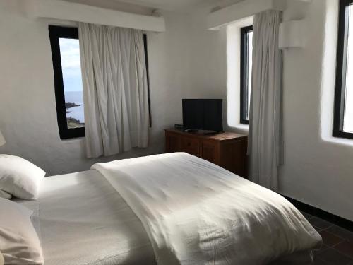 a bedroom with a white bed and a television at Club Hotel Casapueblo in Punta del Este