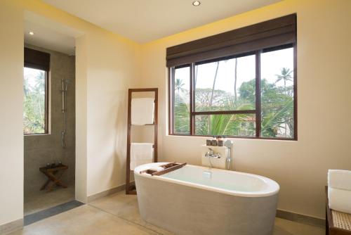 
a bath tub sitting next to a window in a bathroom at Anantara Peace Haven Tangalle Resort in Tangalle
