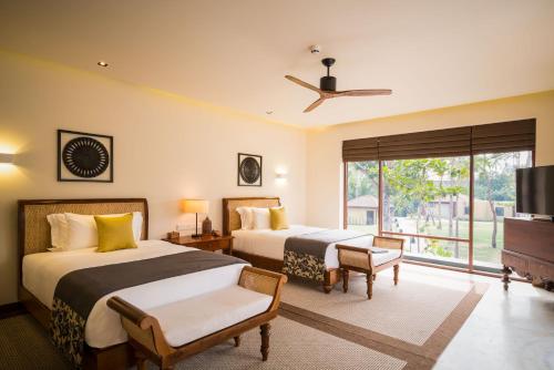 two beds in a hotel room with a tv at Anantara Peace Haven Tangalle Resort in Tangalle