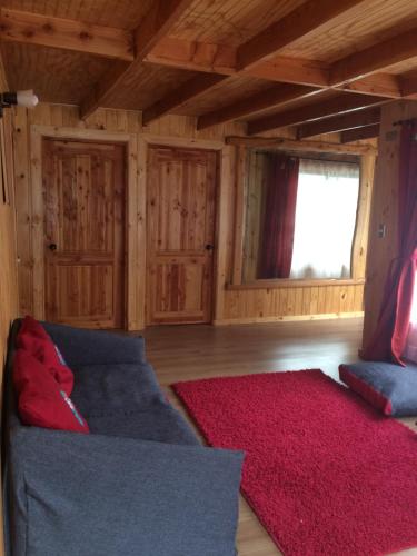 sala de estar con sofá azul y alfombra roja en Cabaña Colibri en San Alfonso