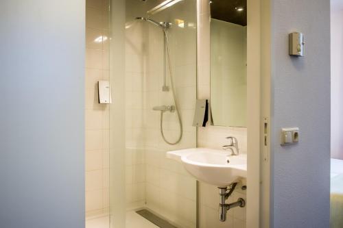 a bathroom with a shower, sink, and mirror at Parkhotel Auberge Vincent in Nuenen