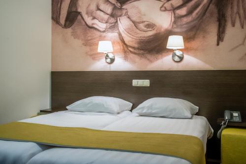 a bed with two pillows and a picture of a woman at Parkhotel Auberge Vincent in Nuenen