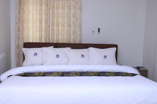 1 cama con sábanas blancas y almohadas blancas en Mawuli Hotel en Obuasi