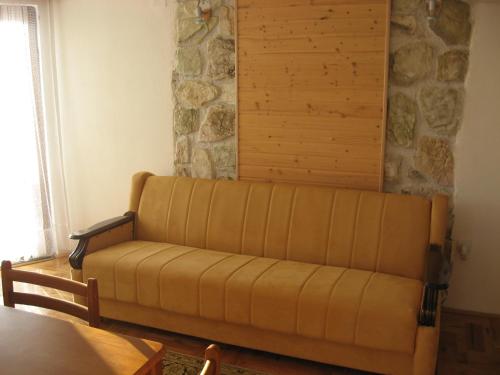 un divano in un soggiorno con parete in pietra di Villa Sofija a Kopaonik