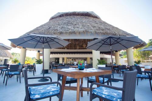 an outdoor restaurant with tables and chairs and umbrellas at Marival Distinct All-Suites & World Spa - Handwritten Collection in Nuevo Vallarta 
