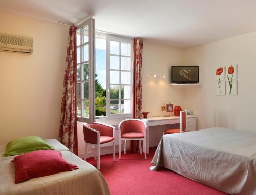 a bedroom with two beds and a desk and a window at Logis Auberge Du Centre in Chitenay