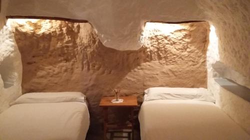 a room with two beds and a table with a glass at Al Jatib in Baza