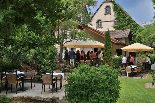 a group of people sitting at tables in a garden at Landidyll Hotel Klostermühle in Münchweiler an der Alsenz