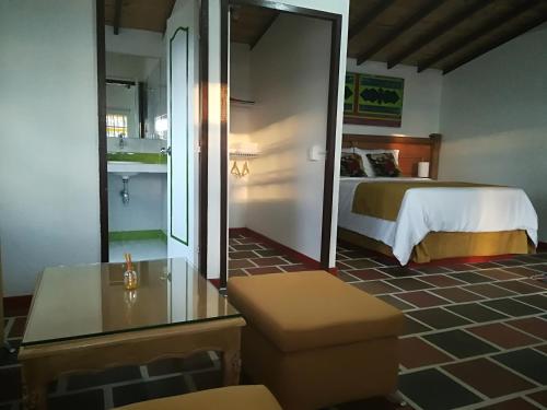 a room with a bed and a table and a mirror at Hotel Zocalo Campestre in Guatapé