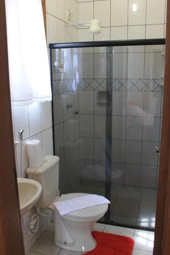 a bathroom with a toilet and a glass shower at Itaporanga Pousada in Santa Maria Madalena