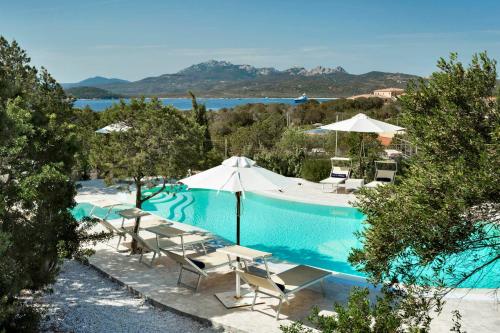 a swimming pool with chairs and umbrellas at Le Case Di Capriccioli in Porto Cervo