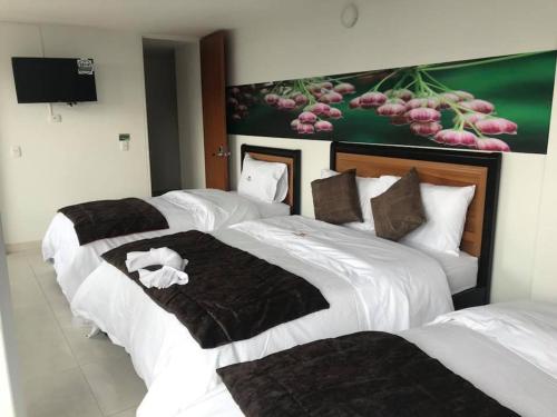 a group of three beds in a hotel room at Hotel Santa Monica in Fusagasuga