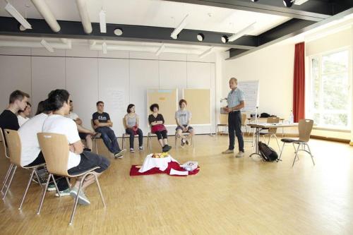 a group of people sitting in chairs in a room with a presentation at Jugendherberge Freiburg in Freiburg im Breisgau