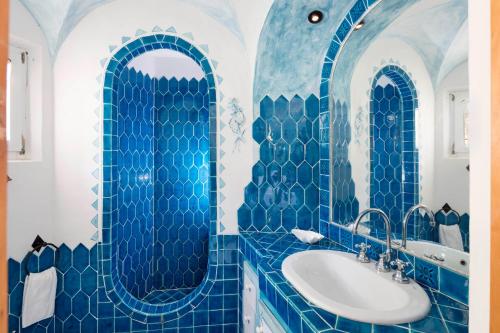 a blue tiled bathroom with a sink and a mirror at Le Case Di Capriccioli in Porto Cervo