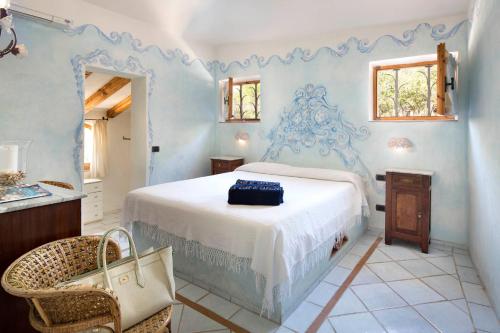 a blue bedroom with a bed and a chair at Le Case Di Capriccioli in Porto Cervo