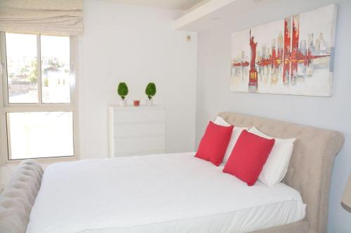 una camera da letto con un letto bianco con cuscini rossi di Sweethome26 Luxury Apartment Eilat / Free Parking a Eilat
