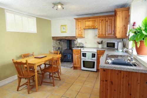 a kitchen with a wooden table and a sink at Scenery Cottage in Bridford