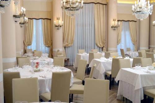a dining room with white tables and chairs and chandeliers at Grand Hotel Vittoria in Montecatini Terme
