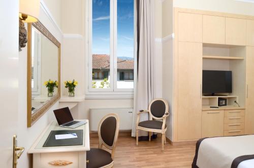 a hotel room with a bed and a desk with a laptop at Grand Hotel Vittoria in Montecatini Terme